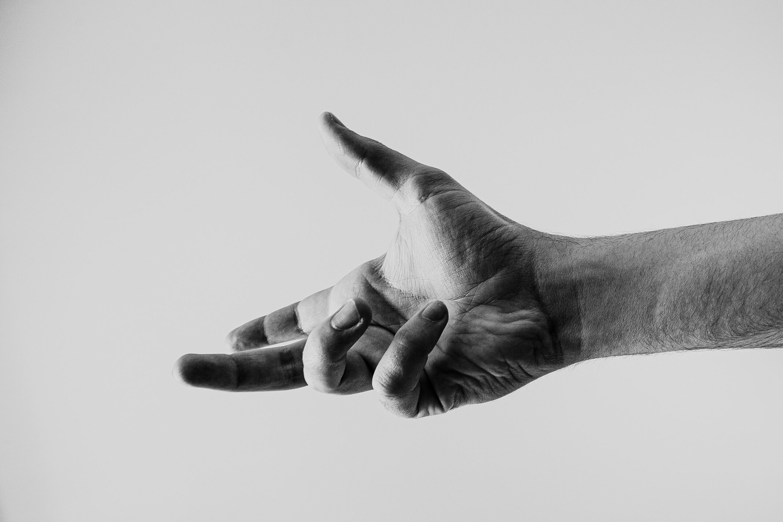 Nahaufnahme der rechten Hand einer Person, die möglicherweise von Morbus Dupuytren betroffen ist, mit gespreizten Fingern und leicht nach oben gerichteter Handfläche vor einem schlichten hellen Hintergrund.